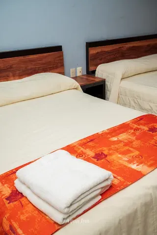 Cama matrimonial con camino de cama naranja · Hotel Aqua Inn